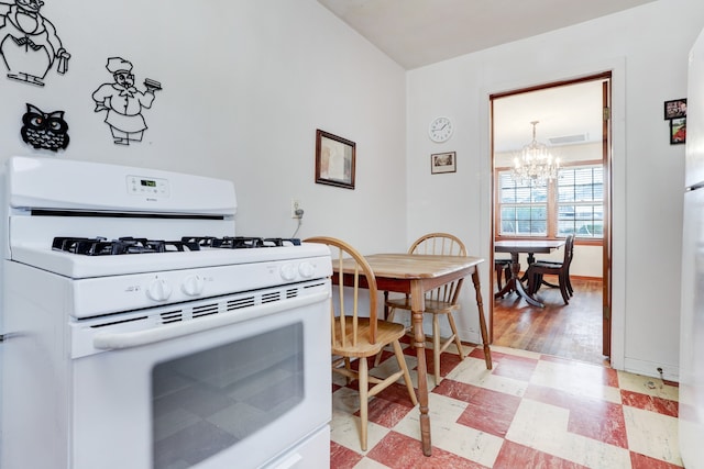 kitchen with light tile patterned floors, white gas range, and an inviting chandelier