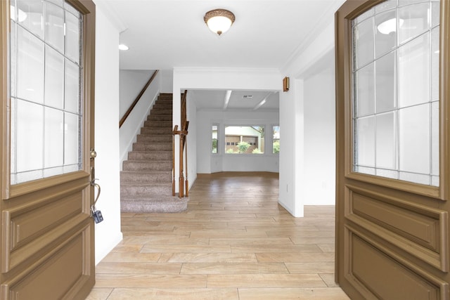 foyer entrance featuring light wood-type flooring, stairs, and ornamental molding