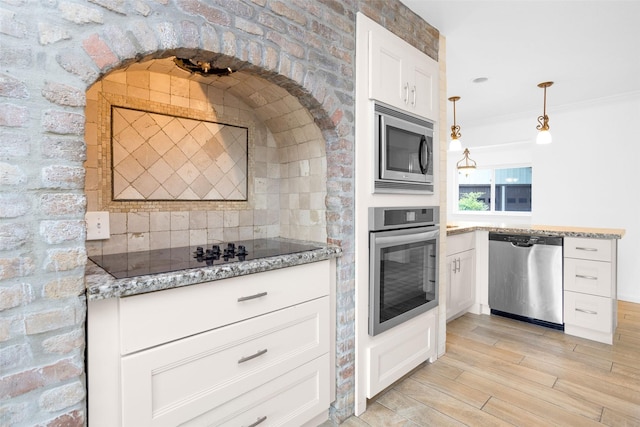 kitchen with light stone counters, hanging light fixtures, appliances with stainless steel finishes, light wood-style floors, and white cabinets