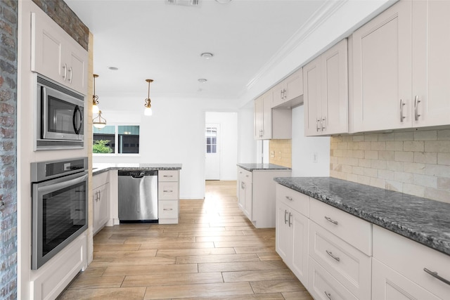 kitchen with ornamental molding, hanging light fixtures, appliances with stainless steel finishes, and white cabinets