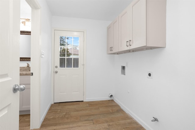 clothes washing area with baseboards, hookup for an electric dryer, cabinet space, and light wood finished floors