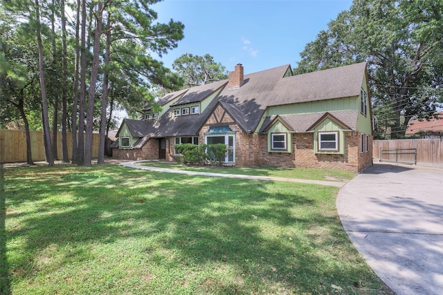 tudor-style house with a front yard, brick siding, and fence