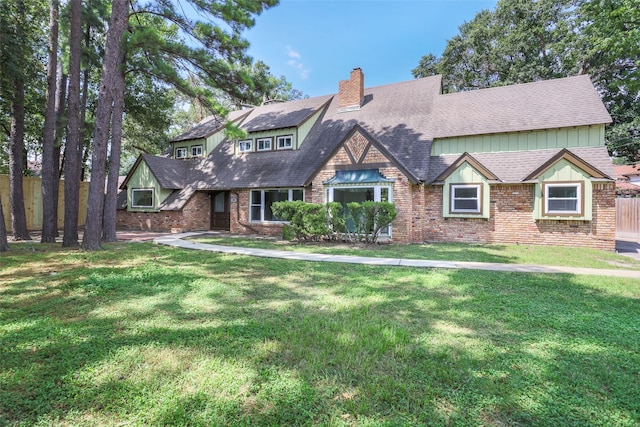 view of front of property featuring a front yard, a chimney, fence, and brick siding