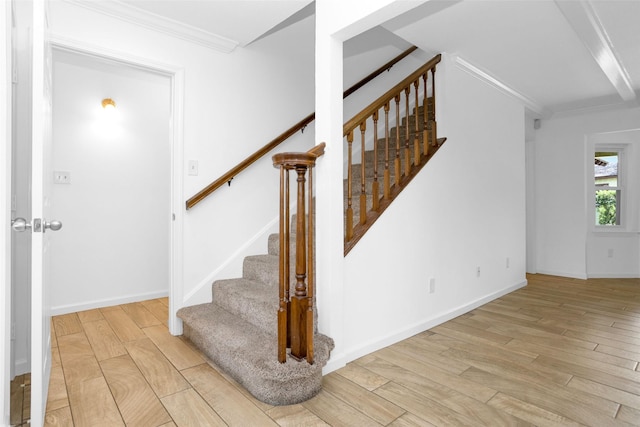 stairway featuring ornamental molding, baseboards, and wood finished floors