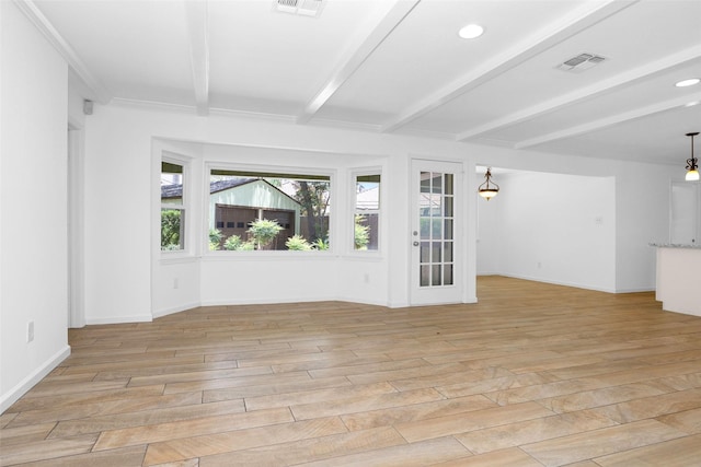 empty room featuring light wood-type flooring, beam ceiling, visible vents, and baseboards