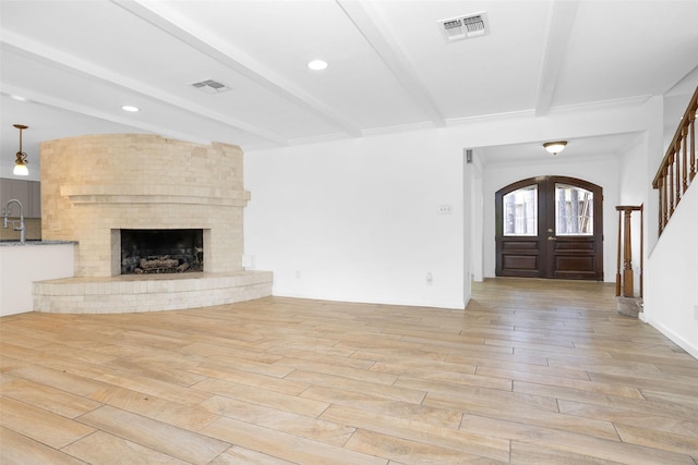 foyer entrance with light wood-style flooring, visible vents, beam ceiling, and french doors