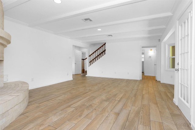 unfurnished living room with beam ceiling, stairway, light wood-style flooring, and baseboards