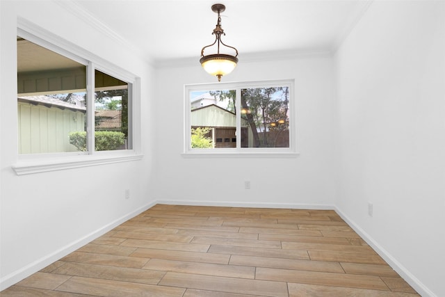 empty room featuring light wood-style floors, ornamental molding, and baseboards