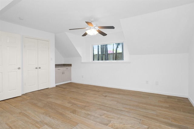 additional living space with light wood-type flooring, baseboards, a ceiling fan, and lofted ceiling