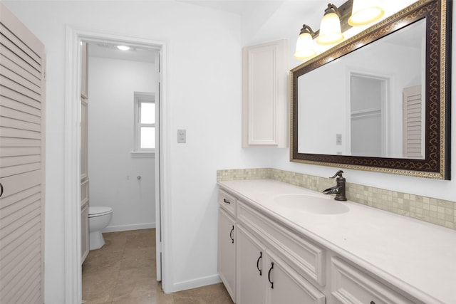 bathroom with toilet, vanity, baseboards, a closet, and tile patterned floors