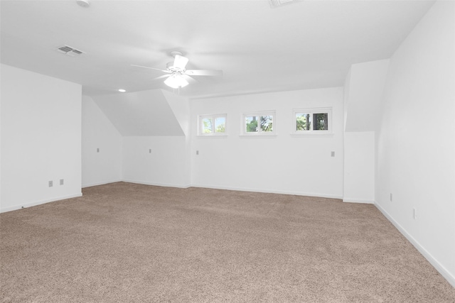 additional living space with visible vents, a ceiling fan, light carpet, vaulted ceiling, and baseboards