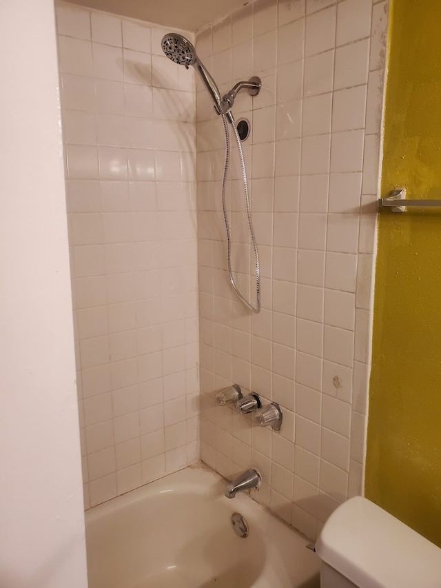 bathroom with tiled shower / bath combo and toilet