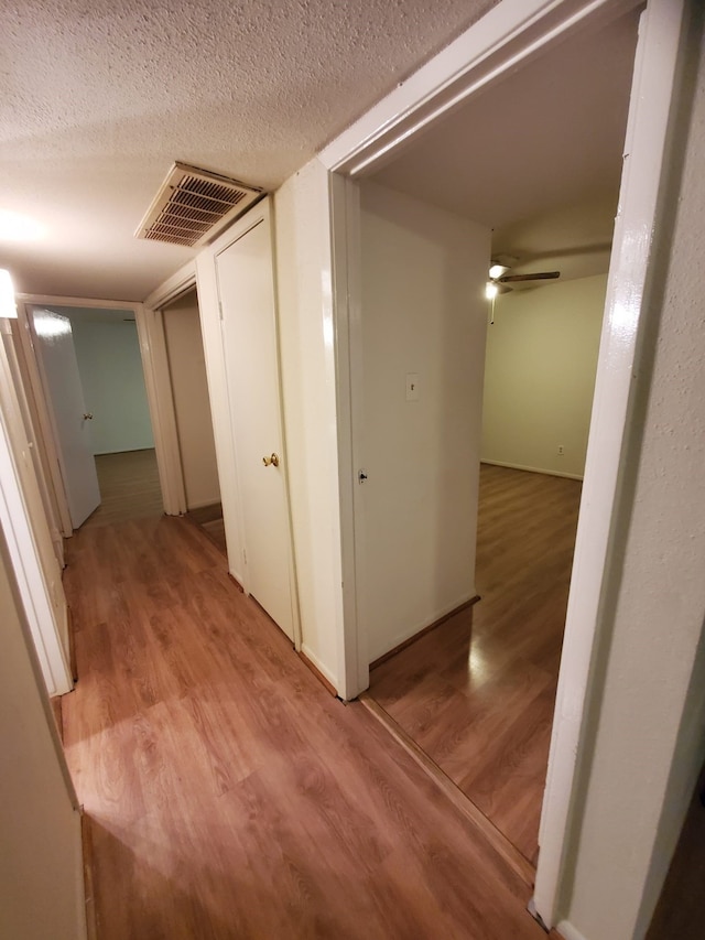 hallway featuring light hardwood / wood-style floors and a textured ceiling