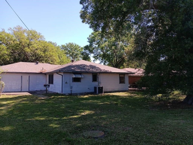 rear view of house with cooling unit and a lawn