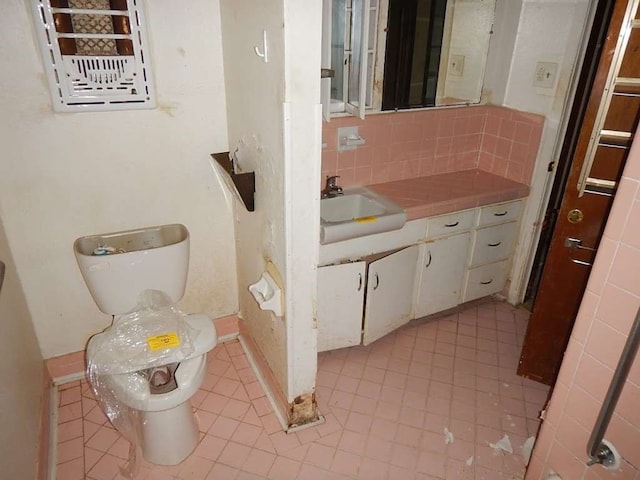 bathroom featuring decorative backsplash, tile patterned floors, toilet, and vanity