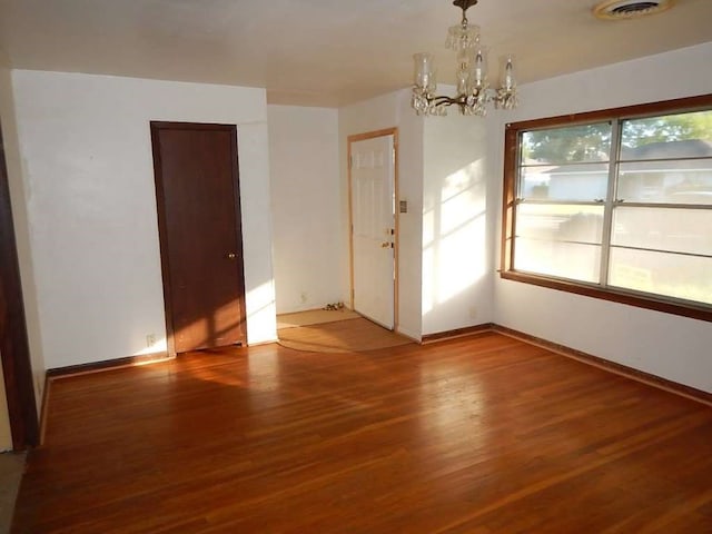 empty room featuring hardwood / wood-style flooring and a chandelier