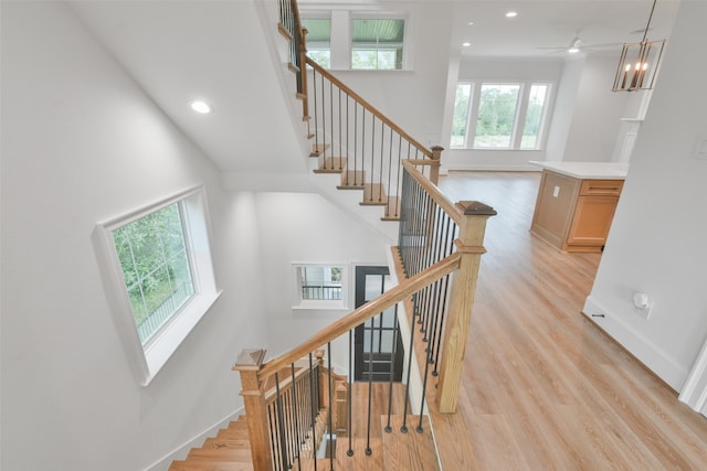 stairs featuring ceiling fan, hardwood / wood-style flooring, and a towering ceiling