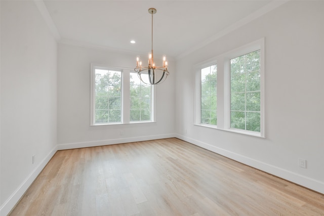 spare room with light hardwood / wood-style flooring, ornamental molding, plenty of natural light, and a chandelier