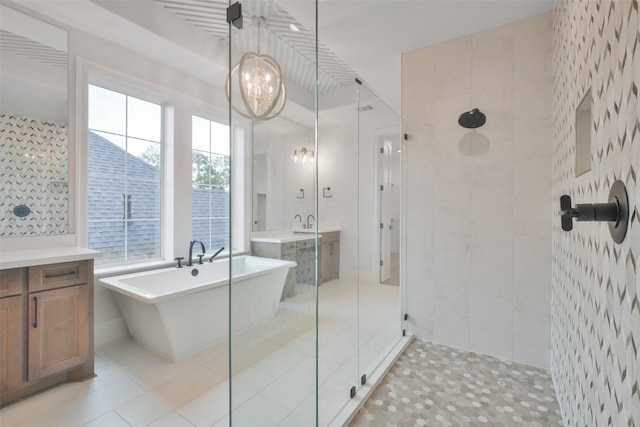 bathroom with a chandelier, tile walls, tile patterned floors, vanity, and separate shower and tub