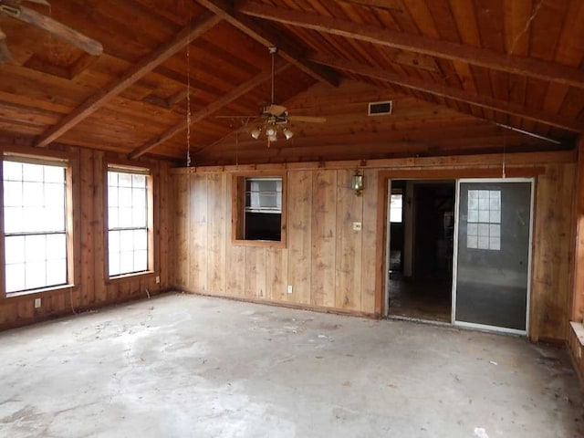 empty room featuring wood ceiling, vaulted ceiling with beams, wooden walls, concrete flooring, and ceiling fan