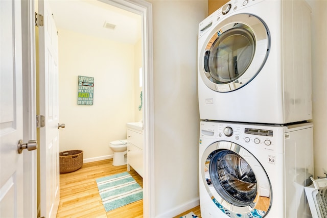 washroom with stacked washer and clothes dryer and light hardwood / wood-style floors