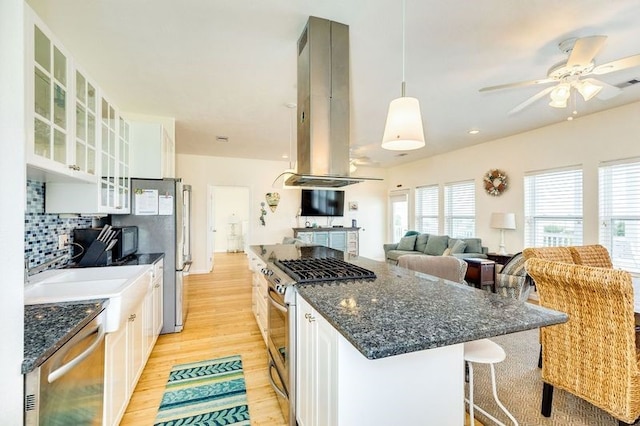 kitchen with pendant lighting, stainless steel appliances, white cabinets, and island exhaust hood