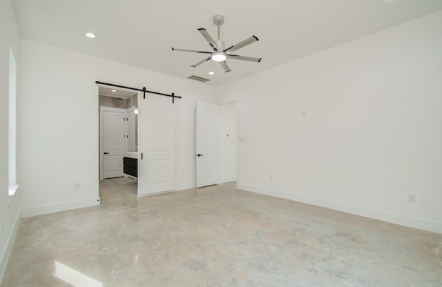 unfurnished bedroom with a barn door and ceiling fan