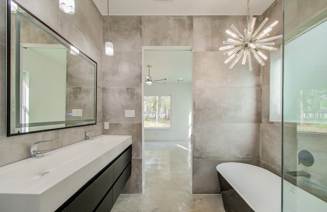 bathroom with concrete floors, a bathtub, ceiling fan with notable chandelier, vanity, and tile walls