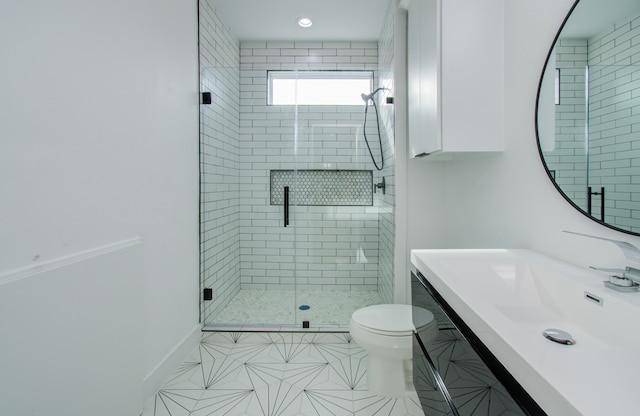 bathroom with tile patterned floors, vanity, toilet, and a shower with door