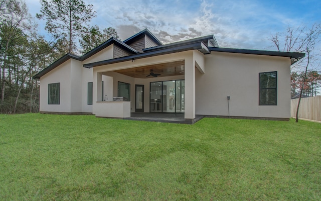 rear view of house with a patio, a lawn, and ceiling fan