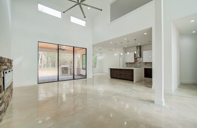 unfurnished living room with ceiling fan, sink, and a high ceiling