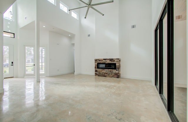 unfurnished living room featuring a fireplace, a notable chandelier, and a high ceiling