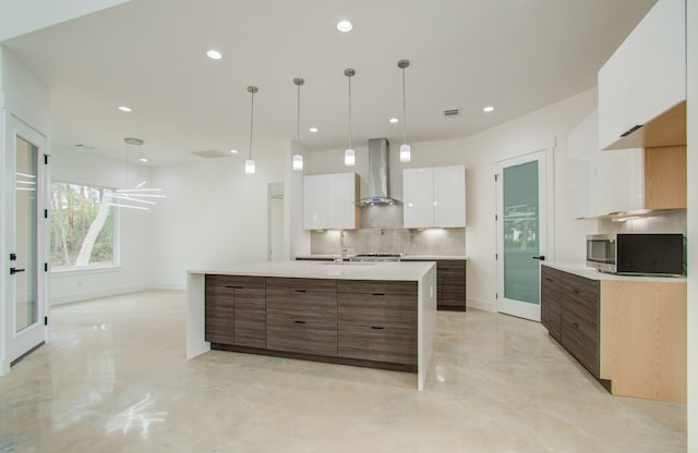 kitchen with white cabinets, backsplash, decorative light fixtures, and wall chimney exhaust hood