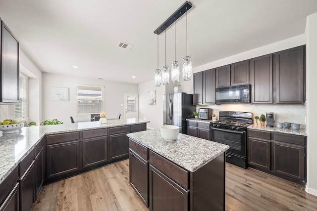 kitchen featuring a center island, pendant lighting, black appliances, and light hardwood / wood-style floors