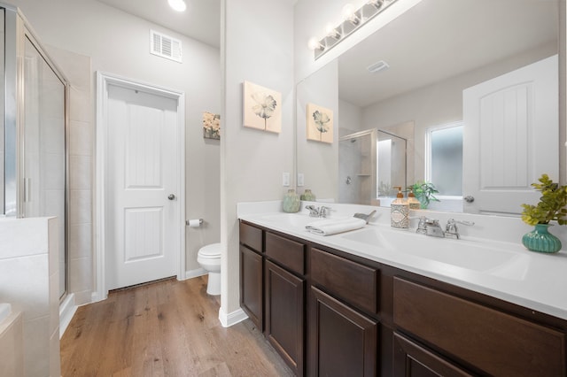 bathroom with an enclosed shower, dual bowl vanity, toilet, and hardwood / wood-style floors