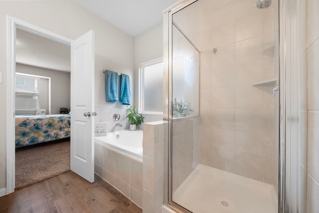 bathroom featuring plus walk in shower and hardwood / wood-style flooring