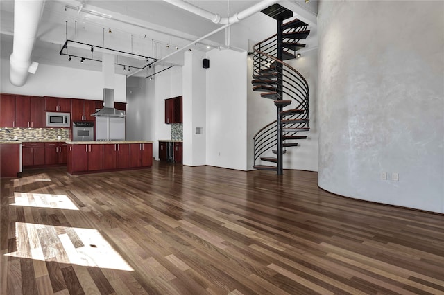 unfurnished living room with a high ceiling, dark hardwood / wood-style floors, and rail lighting