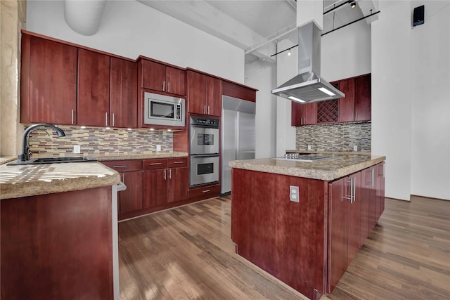 kitchen featuring island exhaust hood, decorative backsplash, built in appliances, and dark wood-type flooring