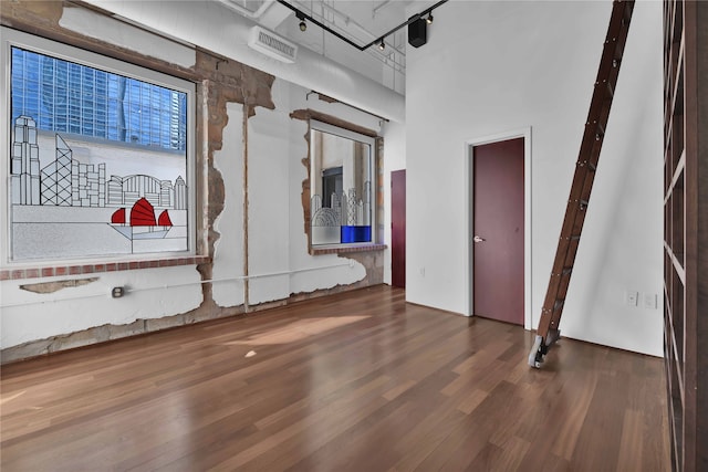 empty room with a towering ceiling and dark hardwood / wood-style flooring