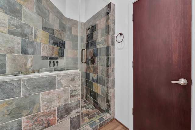 bathroom with a shower with door and hardwood / wood-style floors