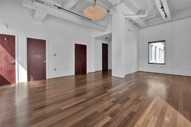 unfurnished living room featuring a towering ceiling and dark hardwood / wood-style floors