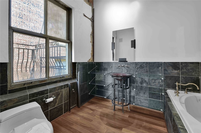 bathroom with hardwood / wood-style flooring, tile walls, toilet, and a tub