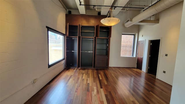 unfurnished bedroom featuring a towering ceiling and dark hardwood / wood-style floors