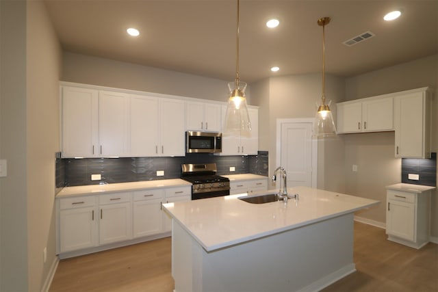 kitchen with white cabinetry, sink, hanging light fixtures, and stainless steel appliances