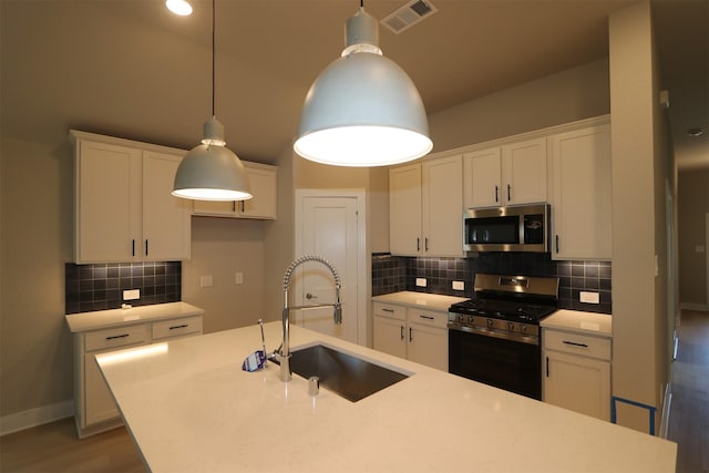 kitchen with stainless steel appliances, white cabinetry, hanging light fixtures, and sink