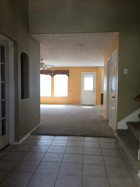 hall with tile patterned flooring and a textured ceiling