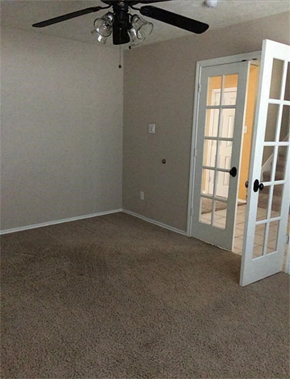 empty room featuring french doors, ceiling fan, and carpet flooring