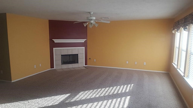 unfurnished living room with carpet floors, a tiled fireplace, and ceiling fan