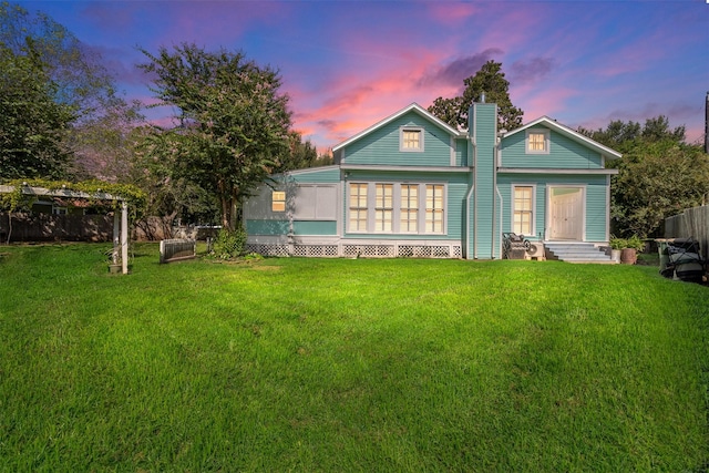 back house at dusk with a lawn