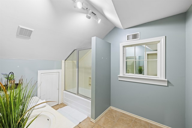 bathroom featuring tile patterned flooring, vaulted ceiling, rail lighting, and enclosed tub / shower combo